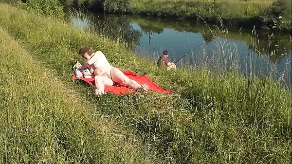 Regarder MILF sexy Frina sur la rive du fleuve se déshabille et prend un bain de soleil nue. Un pêcheur au hasard la surveillait et a finalement décidé de rejoindre une femme nue. Plage sauvage. Plage de nudistes. Nudité publiquePower Tube